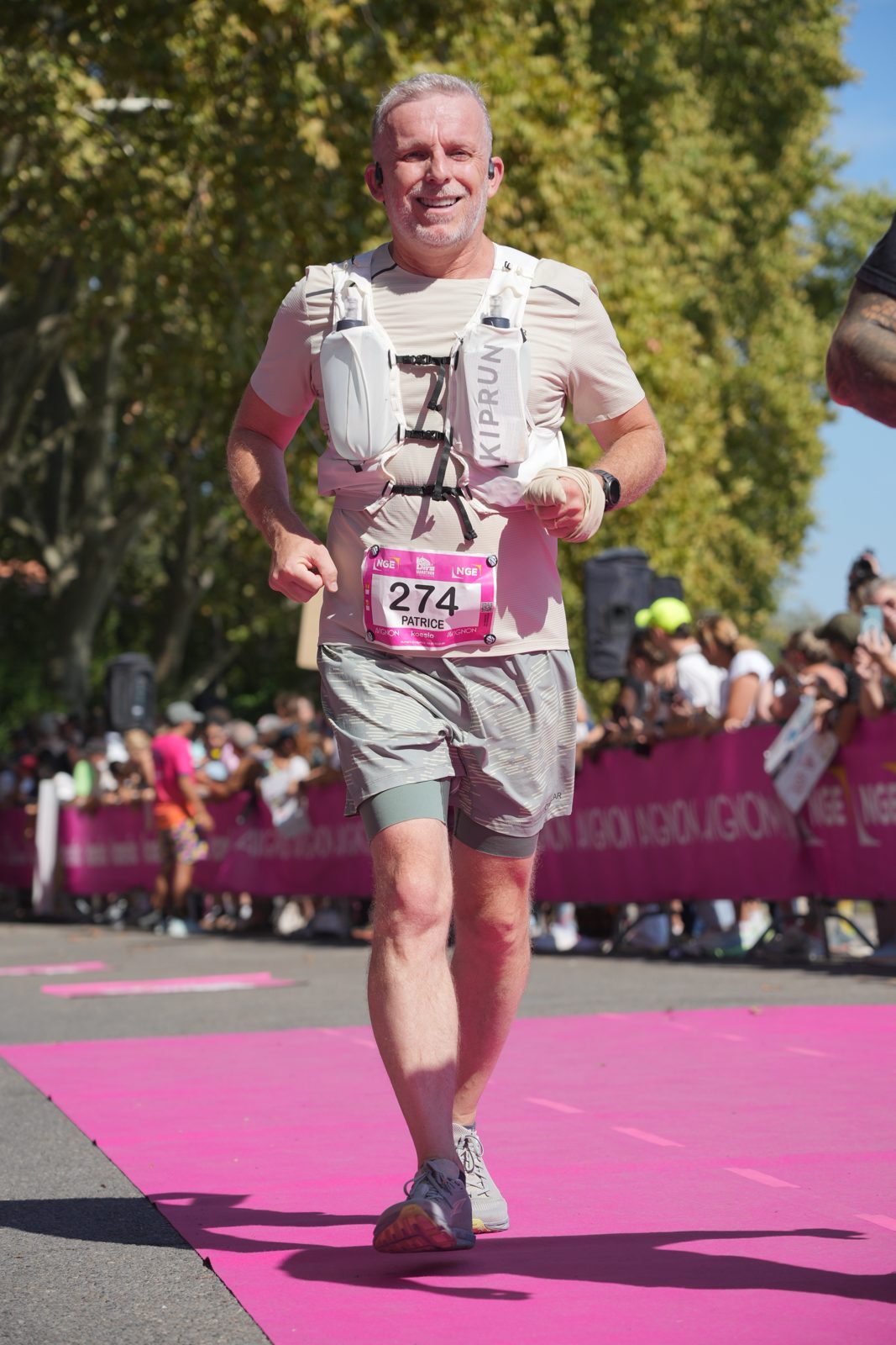 Patrice, dossard 274, souriant sur le tapis rose de l'arrivée du marathon d'Avignon.