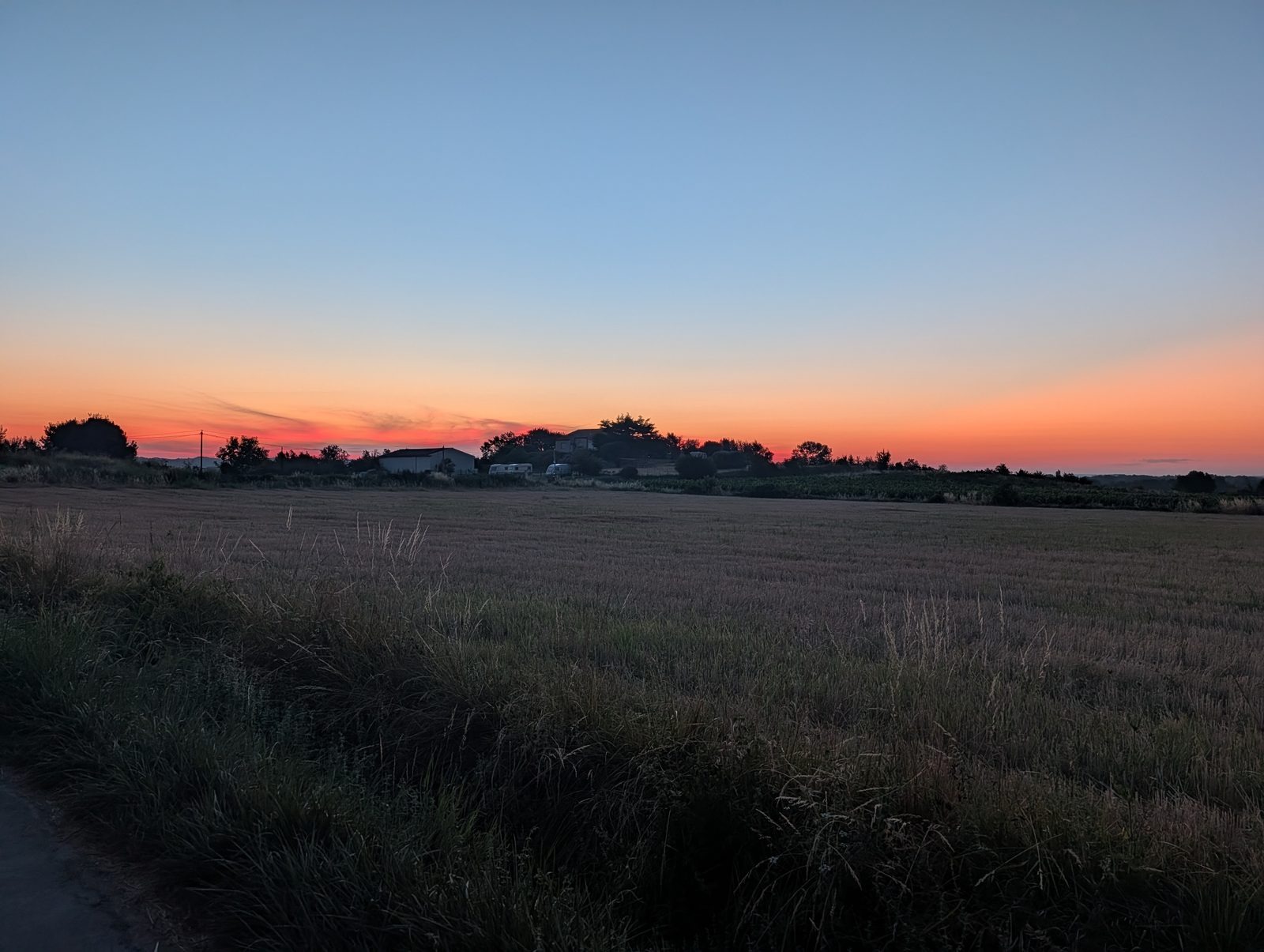 Champ moissonné à l&rsquo;aube, ciel orangé