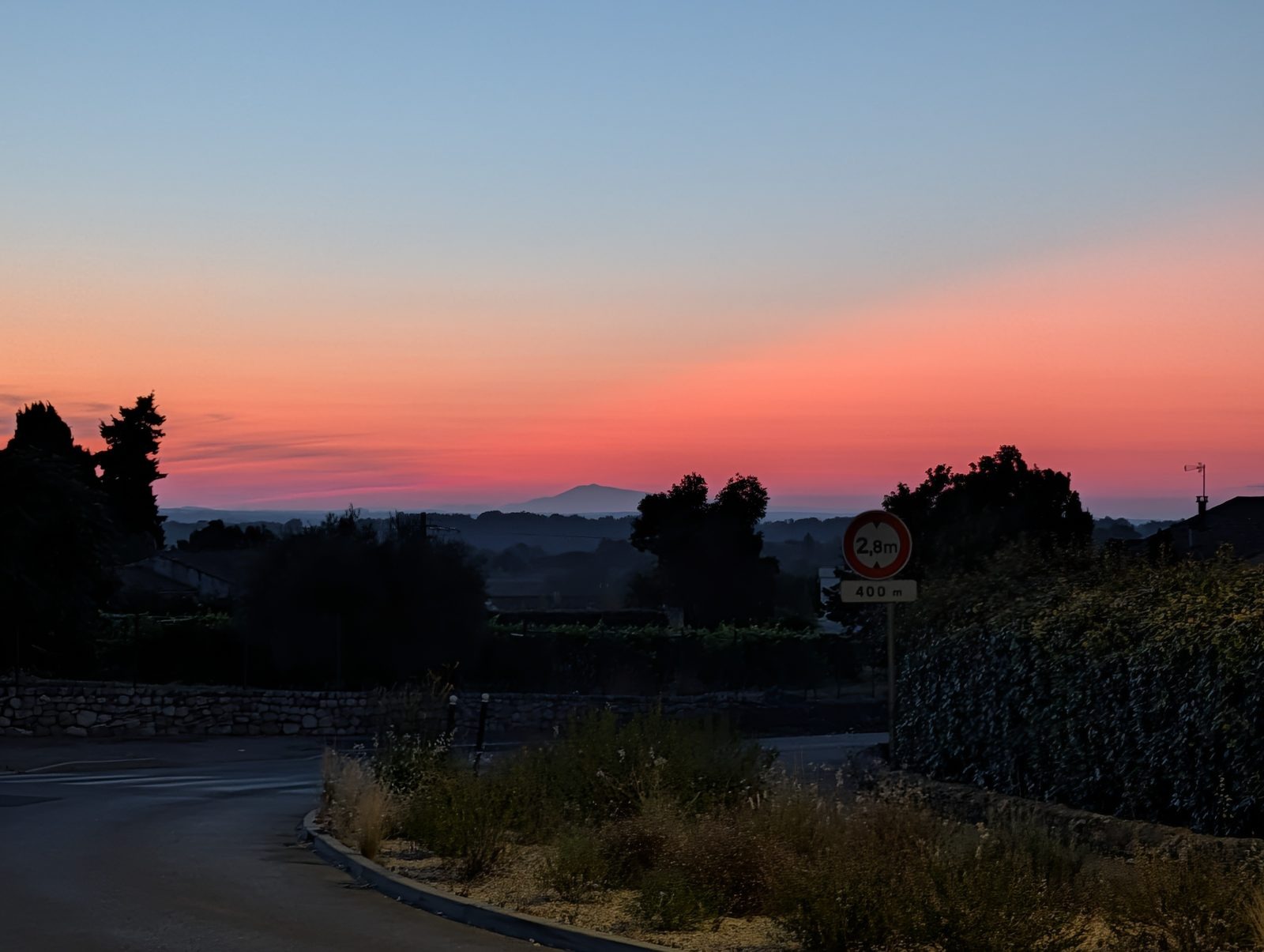 Lever de soleil rose-orangé sur la route, le Mont Ventoux en silhouette à l'horizon