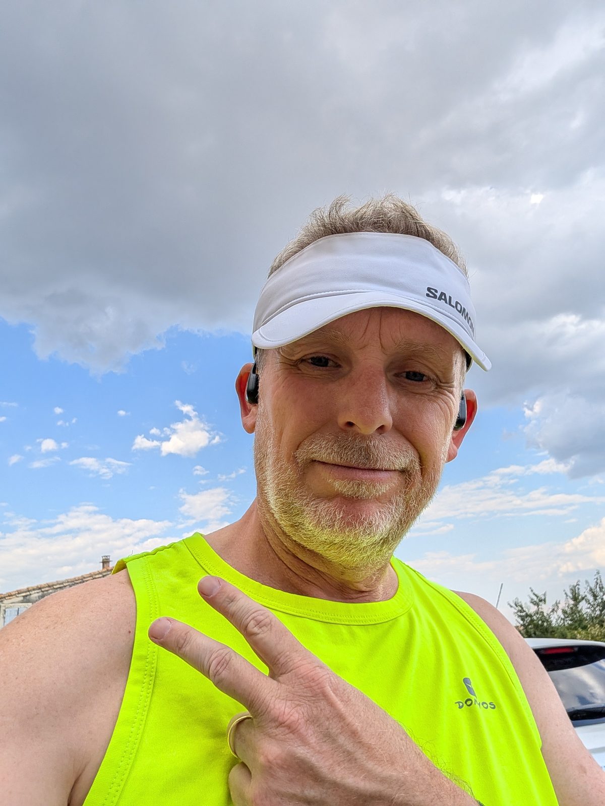 Selfie avant la sortie : visière blanche Salomon, débardeur jaune fluo, signe V de la main, ciel voilé mais lumineux au-dessus du Gard.